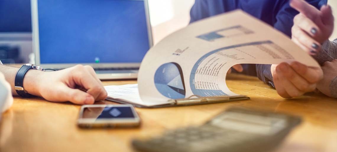Anonymous Business Meeting with diagram, charts, laptop smartphone and hands, selective focus: flipping a page